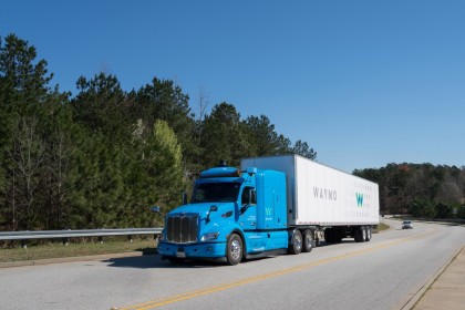 A blue, Waymo Via truck on a freeway