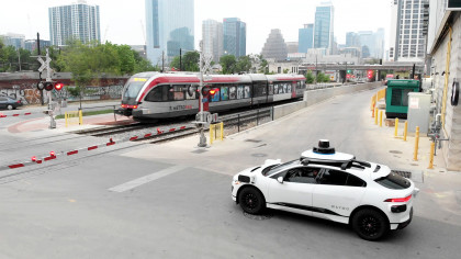 Waymo car waiting for train to pass in Downtown Austin