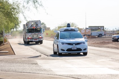 A photo of a white, Waymo Pacifica minivan yielding to a firetruck at a closed course testing facility 