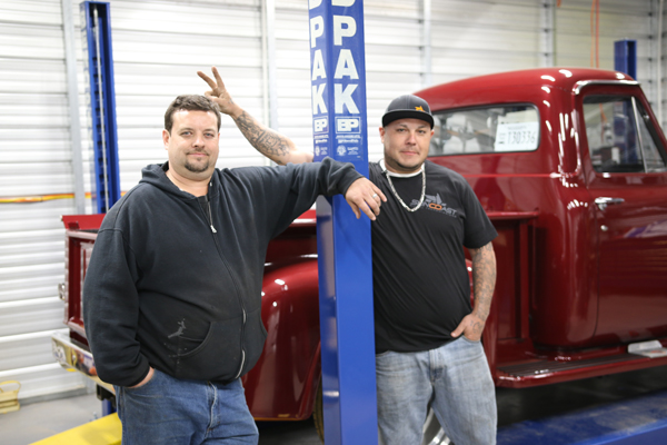 Mechanics In Garage With Classic Truck And BendPak Lift