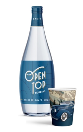 A bottle of Open Top-branded Elderflower soda stands beside a paper cup bearing an illustration of the vintage vehicle.