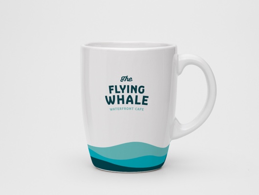 A coffee cup from the onsite Flying Whale Waterfront Cafe features a decorative wave motif.