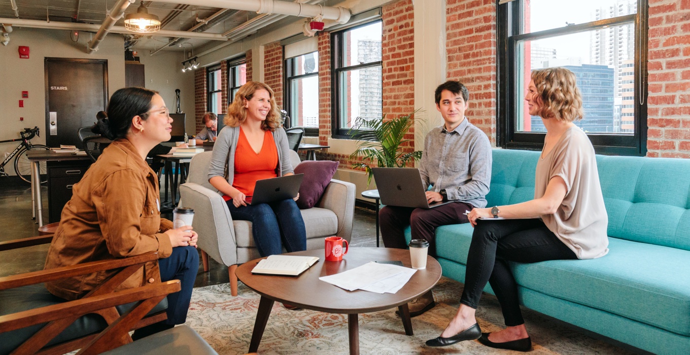 Four employees meeting around a coffee table.

