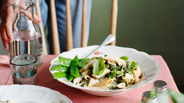 Pasta och kyckling i skålar på ett bord.