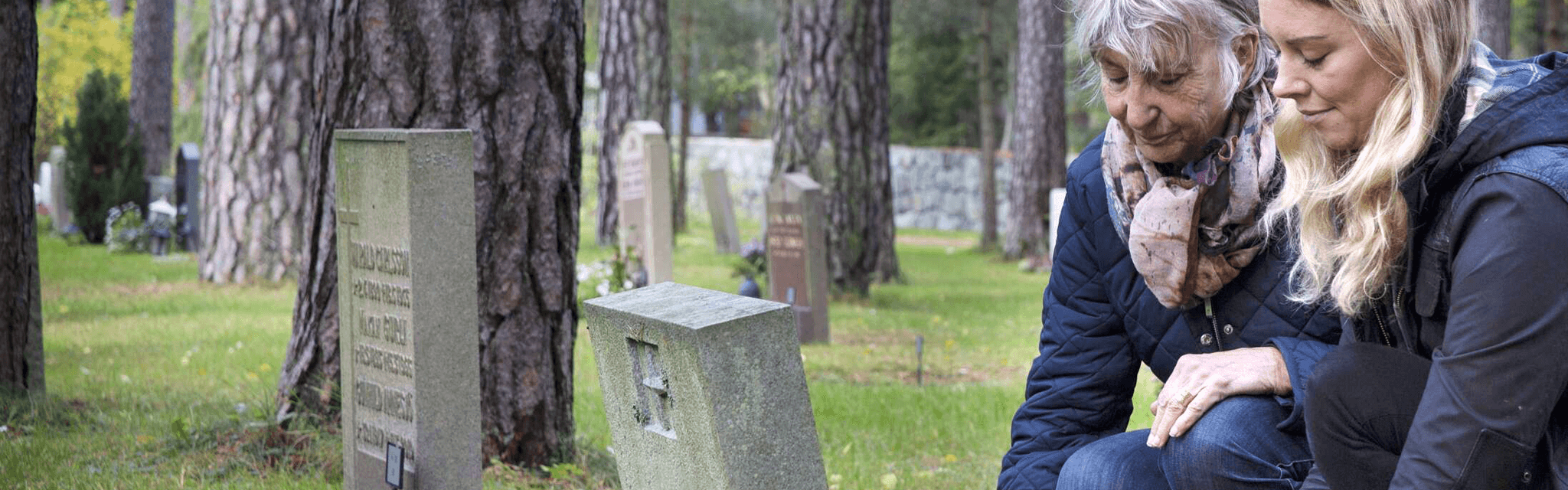 Två personer besöker en gravplats
