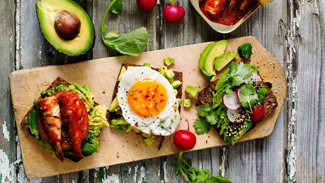 Tre mackor med avokado på en skärbräda. 