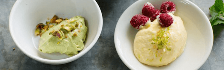 Avocadoglass med pistagenötter i en skål, på ett bord.