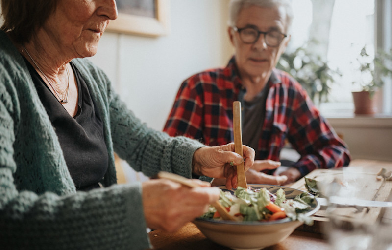 Äldre par äter sallad vid matbordet