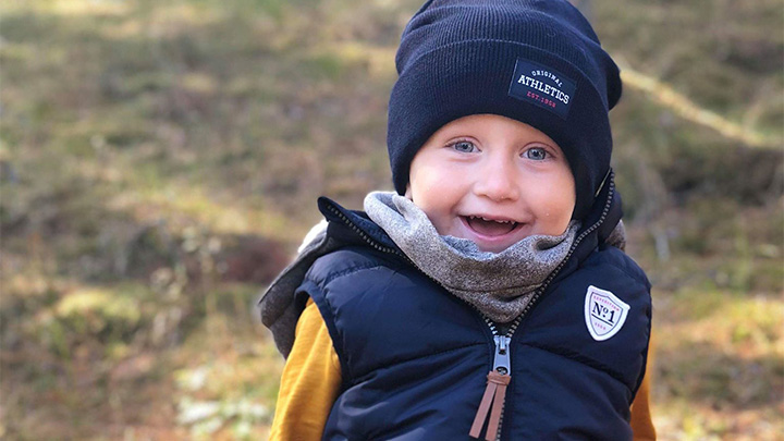 Pojke med blå mössa och väst i höstlandskap