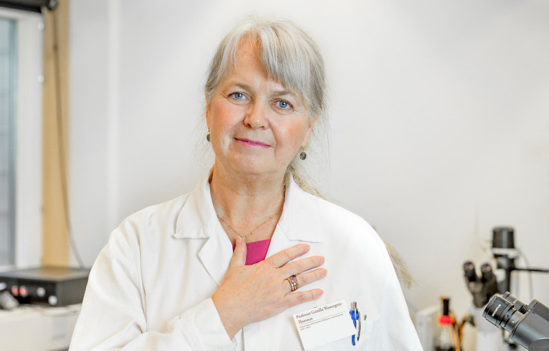 Kvinnlig forskare i vit rock håller handen på hjärtat