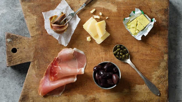 Ost, oliver, en buljongtärning med mera på en skärbräda.