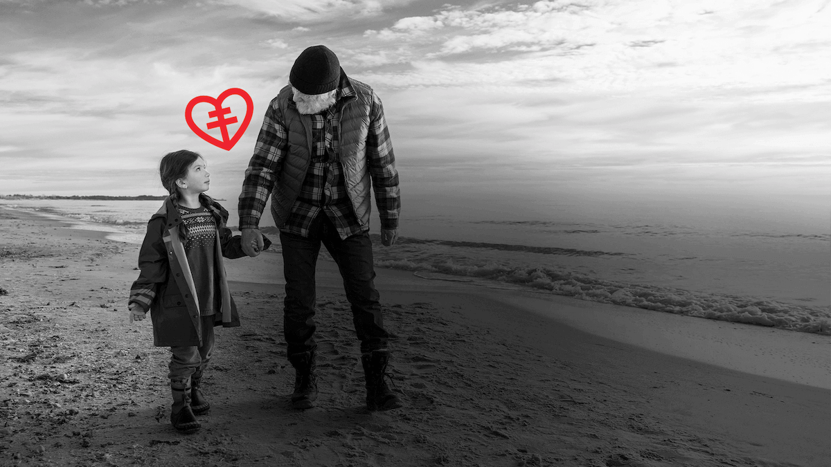 Barn och morfar håller handen på stranden