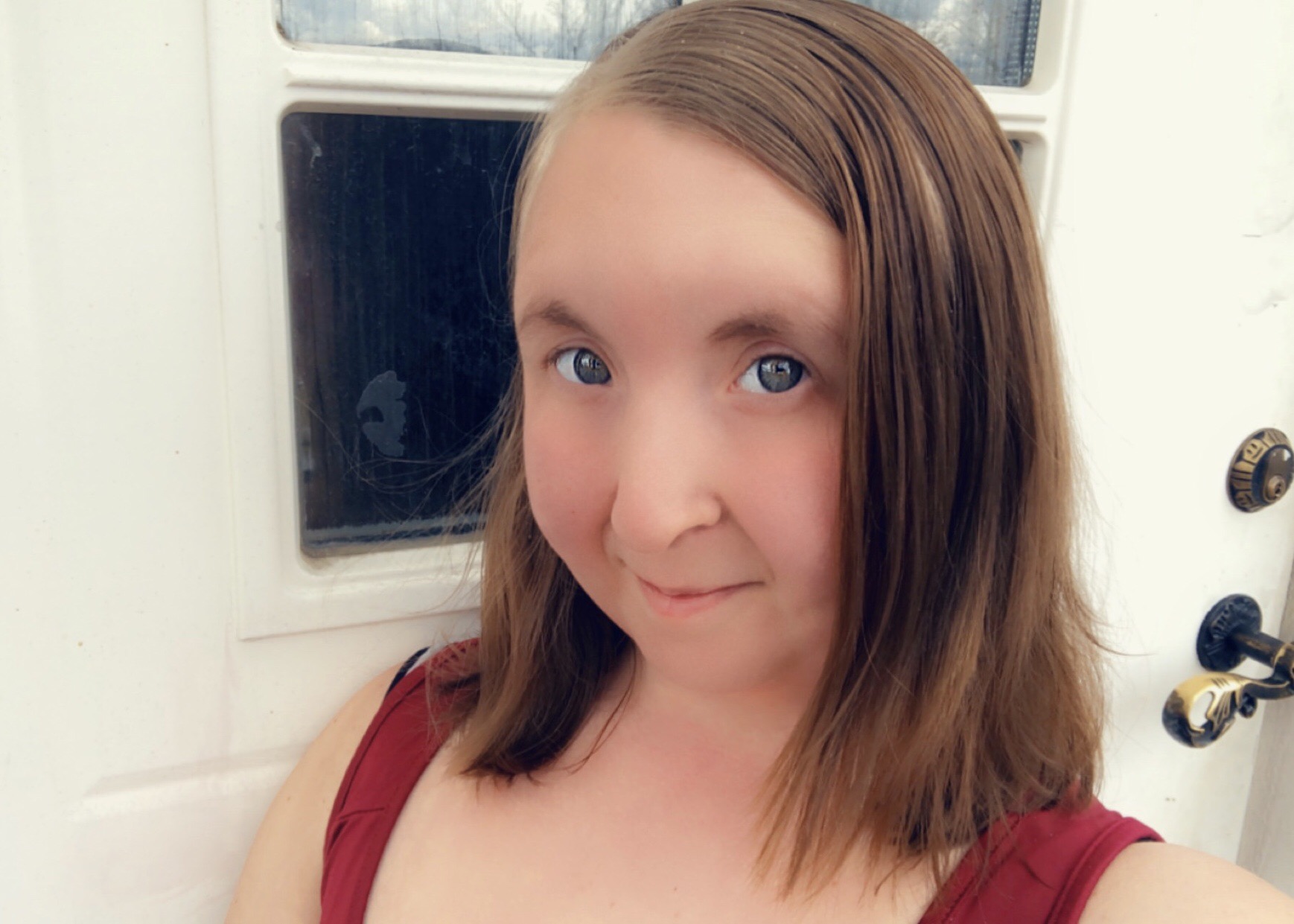 Ung tjej med brunt hår framför vit ytterdörr