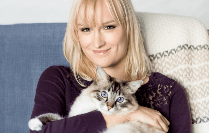 Ung kvinna i soffa med katt i famnen