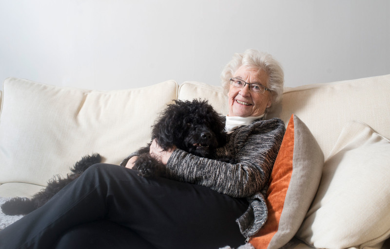 Äldre kvinna i soffa med en hund i famnen