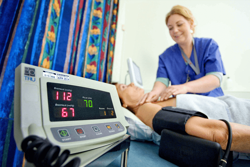 Sköterska tar prov och mäter blodtryck på en patient