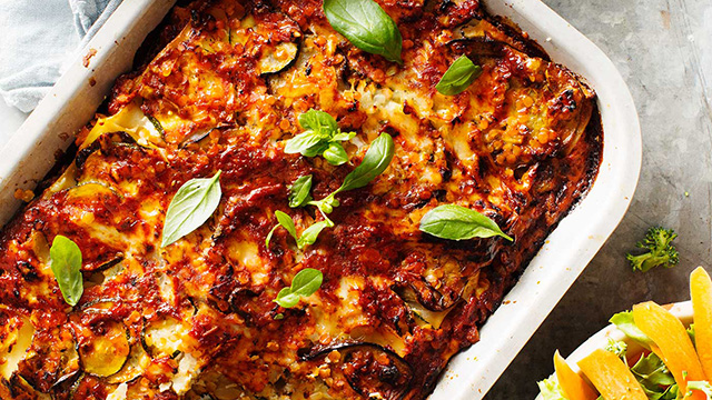 Skördelasagne toppad med basilika i en ugnsform
