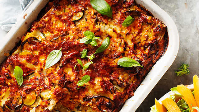 Skördelasagne toppad med basilika i en ugnsform