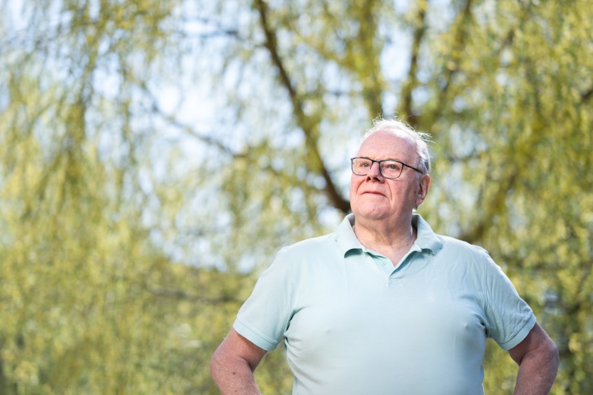 Man i glasögon står framför ett träd