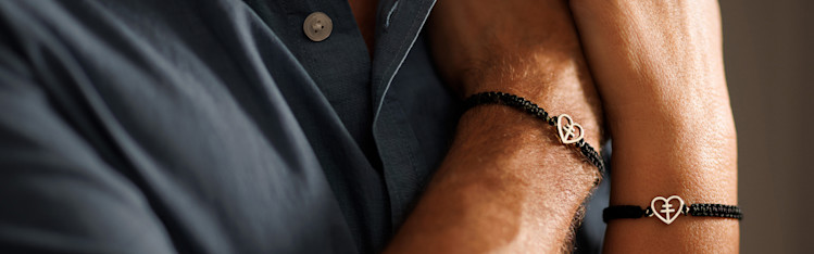 Närbild på två armar med Hjärt-Lungfondens guldarmband.