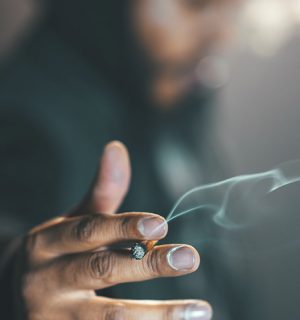 Händer som håller en rykande cigarett