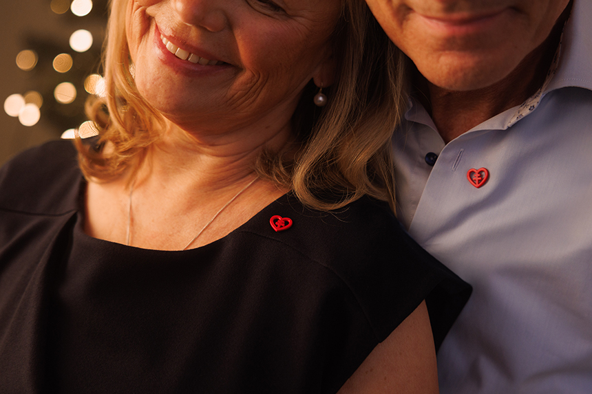 Ett par står leendes tätt bredvid varandra, båda bär Hjärt-Lungfondens röda pin.