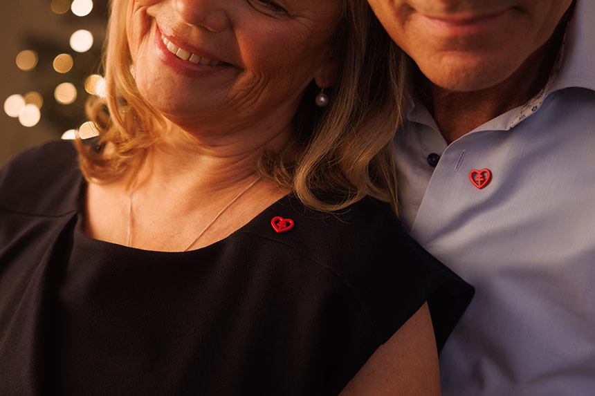 Ett par står leendes tätt bredvid varandra, båda bär Hjärt-Lungfondens röda pin.