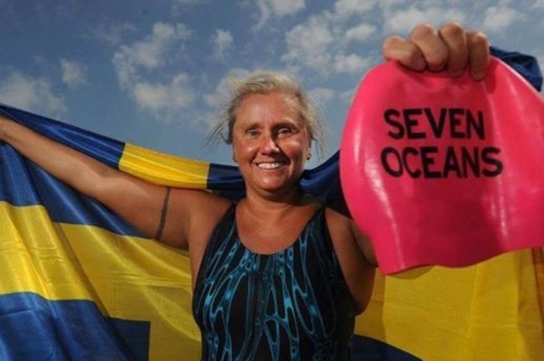 Simmare som håller i en badmössa och svenska flaggan