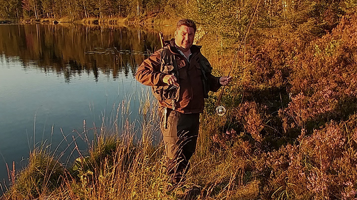 Man med fiskespö vid sjö på hösten