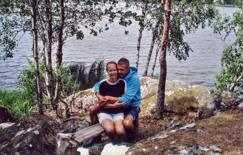 Ungt par håller om varandra på en bänk vid en sjö