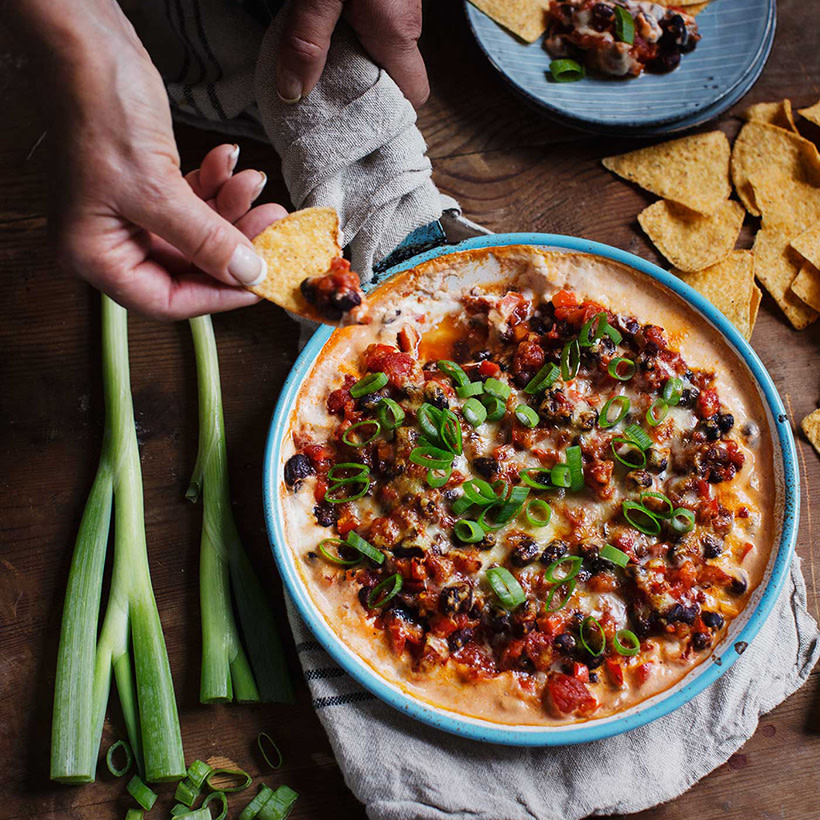 Person dippar nachochips i varm tex-mexdipp