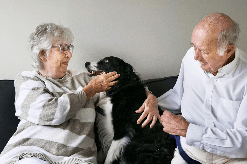 En kvinna med sin hund och man i soffa