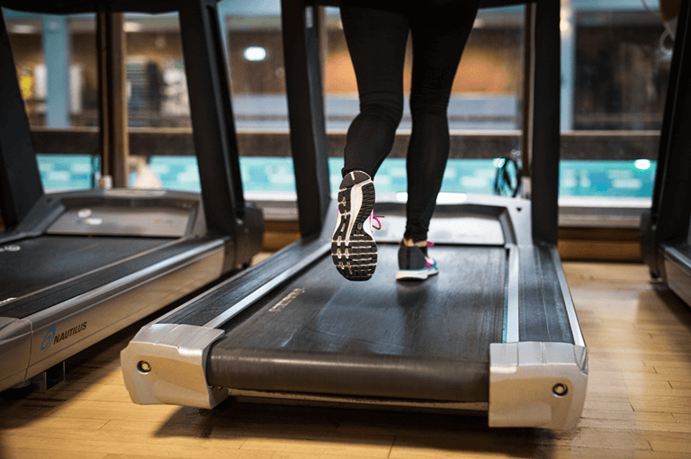Person i svarta träningsbyxor springer på ett löpband