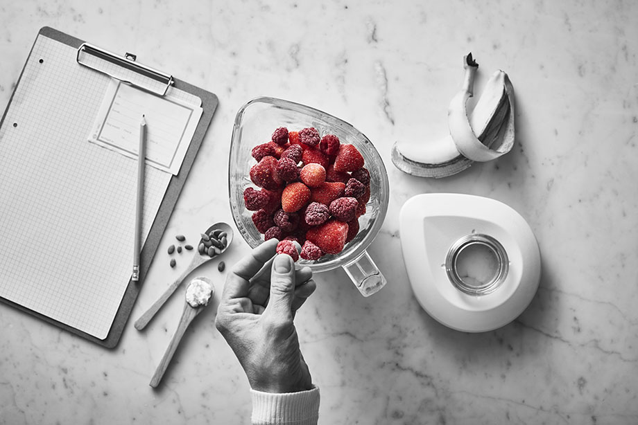 Hand som håller en glasskål med hallon