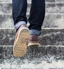 Fötterna på person som går upp för trappan