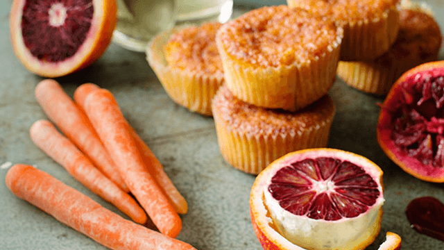 Muffins med bland annat morot, i ett stilleben på ett bord med grönsaker.