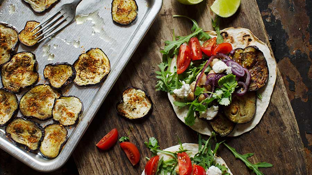 Tacos på en skärbräda och stekt aubergine på en form.
