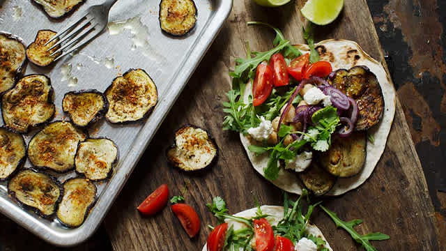 Tacos på en skärbräda och stekt aubergine på en form.