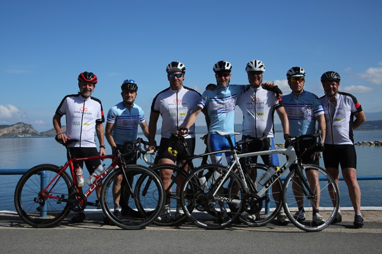 Grupp av manliga cyklister framför sjö