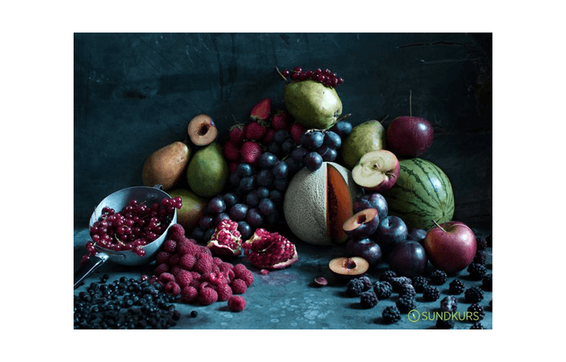 En stor hög med frukt och bär på ett bord