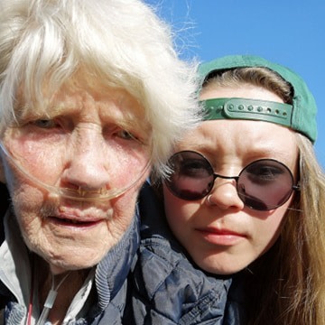 Äldre kvinna med syrgasslang och tonåring med bakåtvänd keps