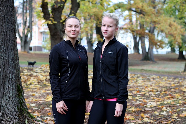 Två unga tjejer i träningskläder i en park med höstlöv