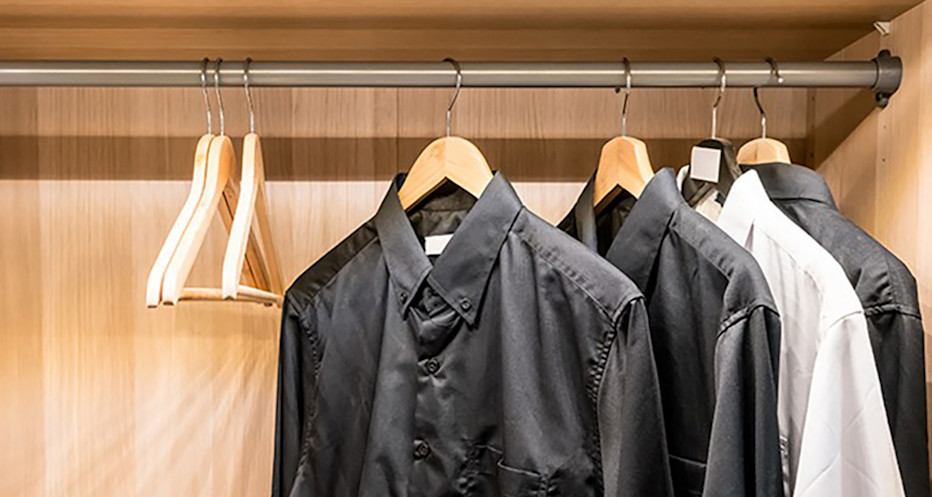 Svarta och vita skjortor hänger på galgar i en garderob.