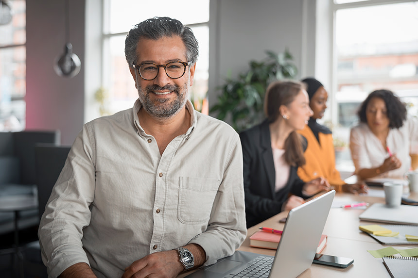Glad man vid laptop på kontor.