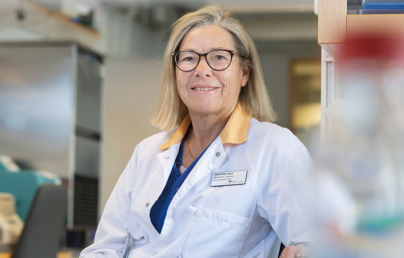 Christina Jern, forskare, sitter ner med en vit rock på sig och ler.