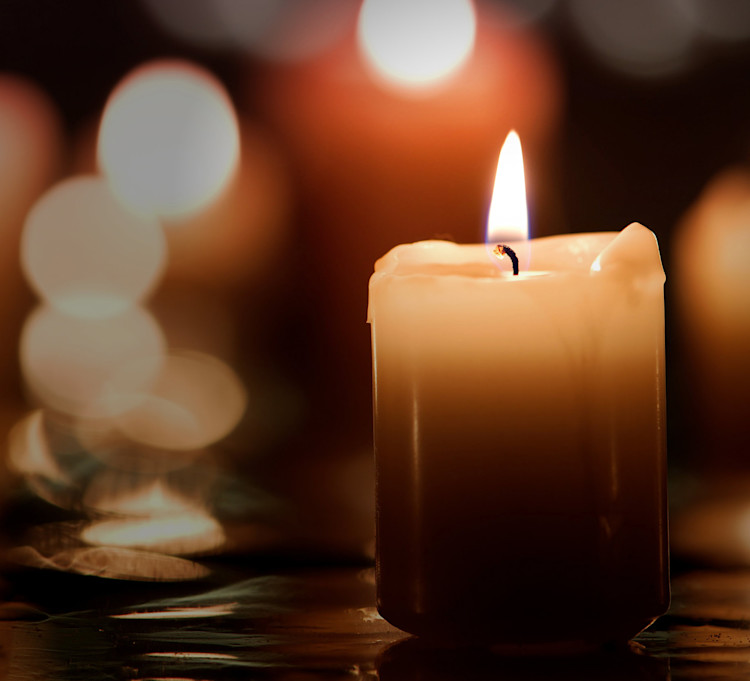 Digital minneslund, vitt ljus mot mörk bakgrund med fler suddiga ljus i bakgrunden.