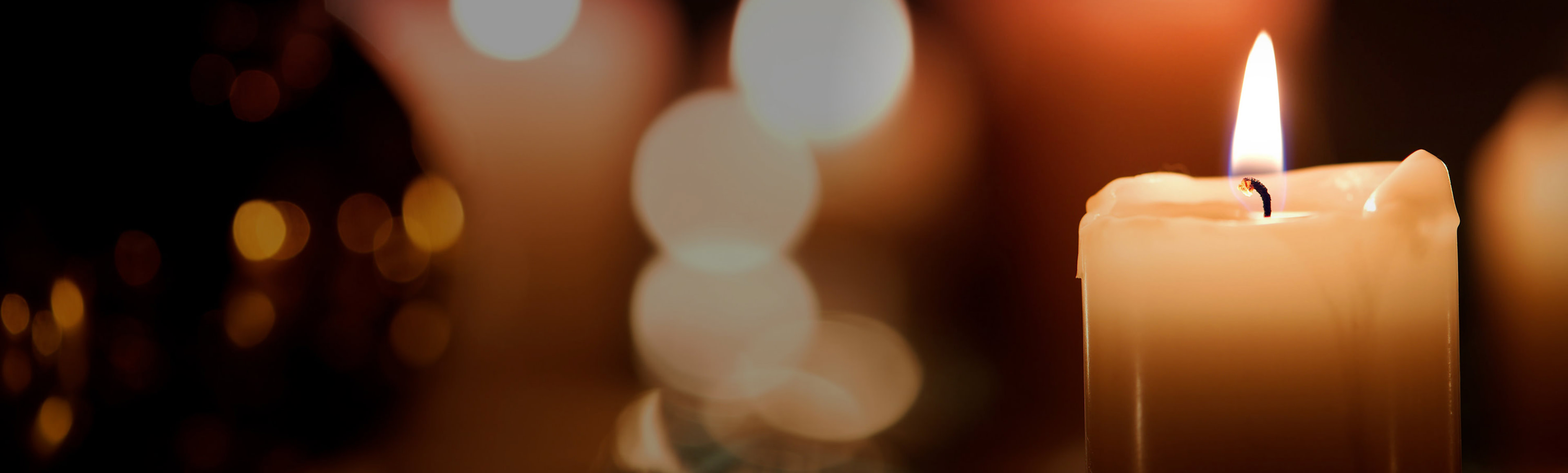 Digital minneslund, vitt ljus mot mörk bakgrund med fler suddiga ljus i bakgrunden.