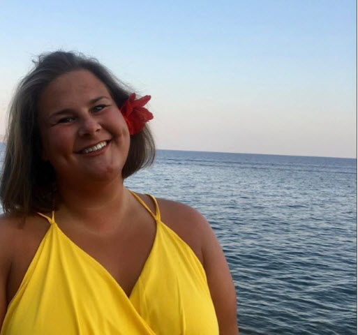 Kvinna med gul sommarklänning och röd blomma i håret