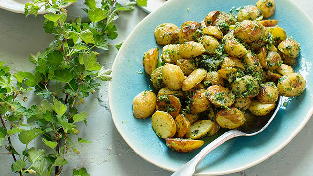 Rostad potatissallad med örtolja upplagt på ett fat.
