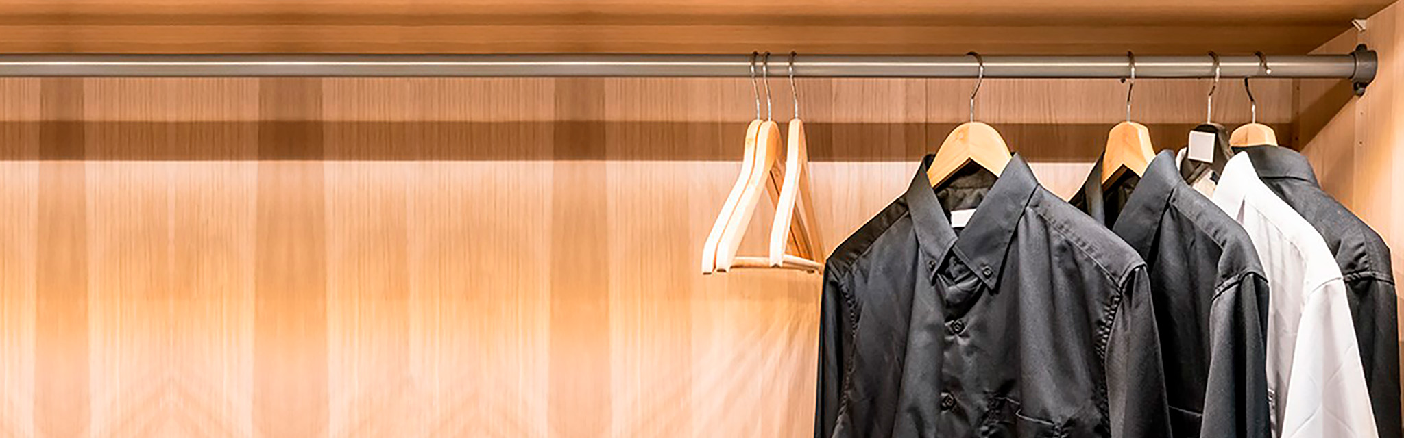 Svarta och vita skjortor hänger på galgar i en garderob.